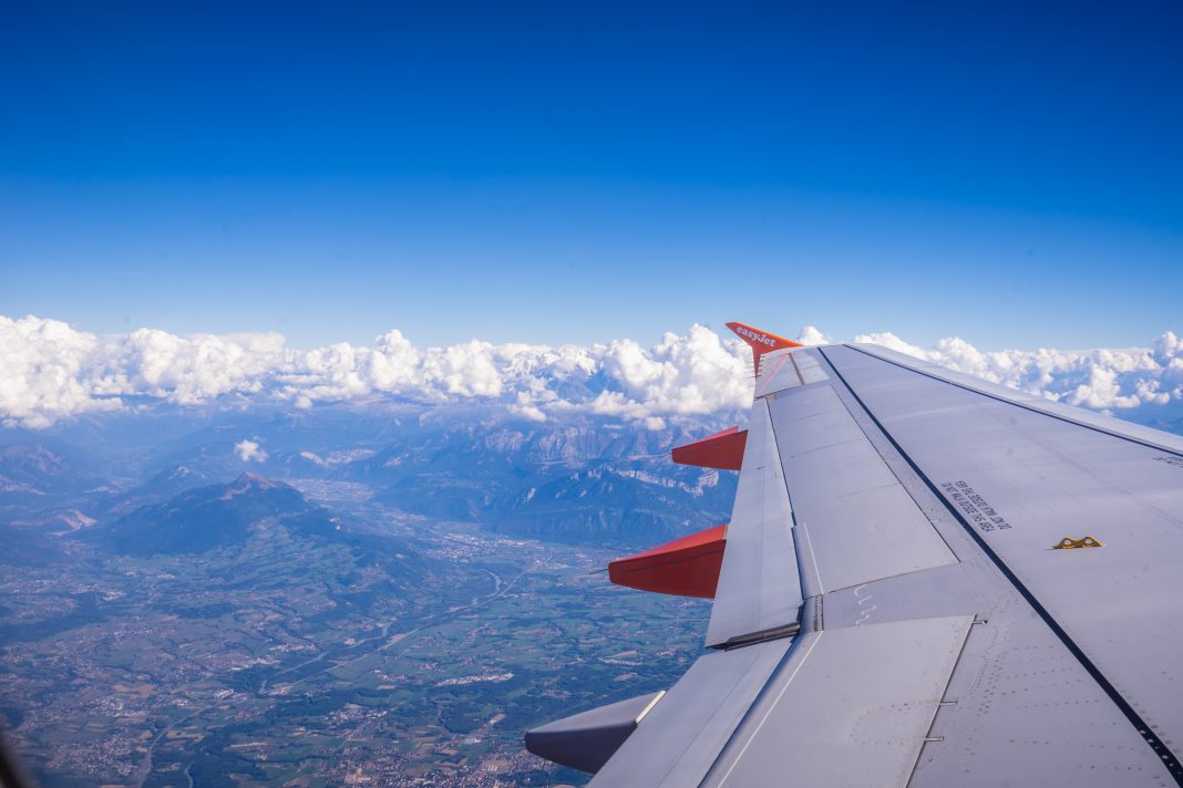 Airplane wing above clouds and mountains