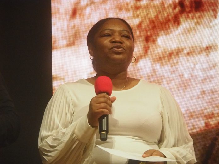 Person speaking with red microphone on stage.