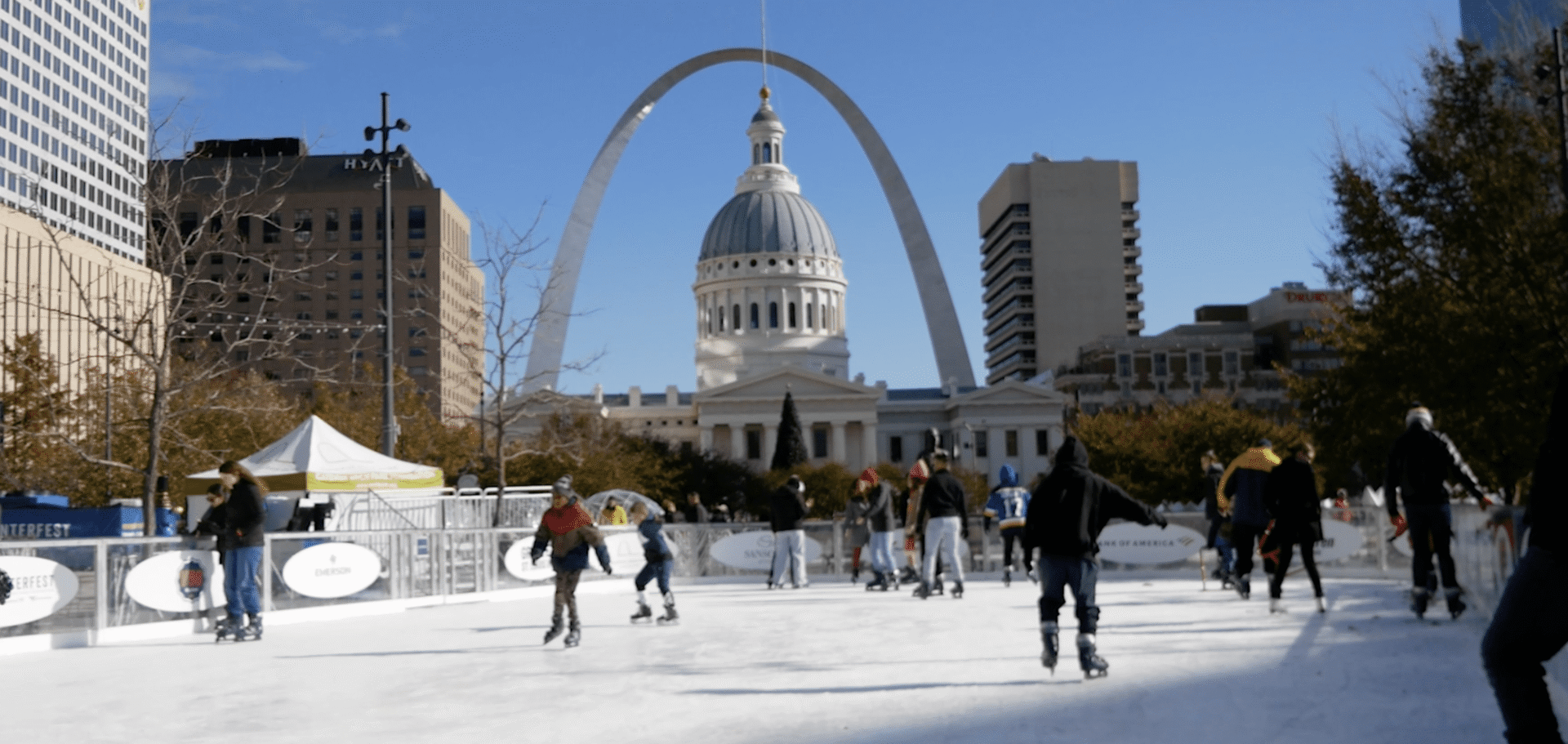Ice rink bustling with skaters under clear sky
