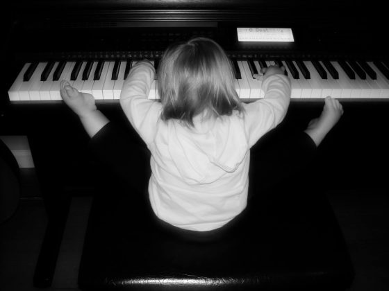 Toddler stretching while playing keyboard