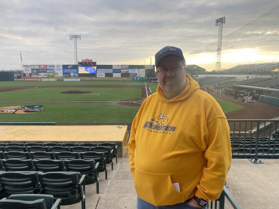 Man in yellow hoodie at baseball stadium