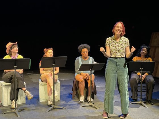 Woman speaking on stage with seated audience.