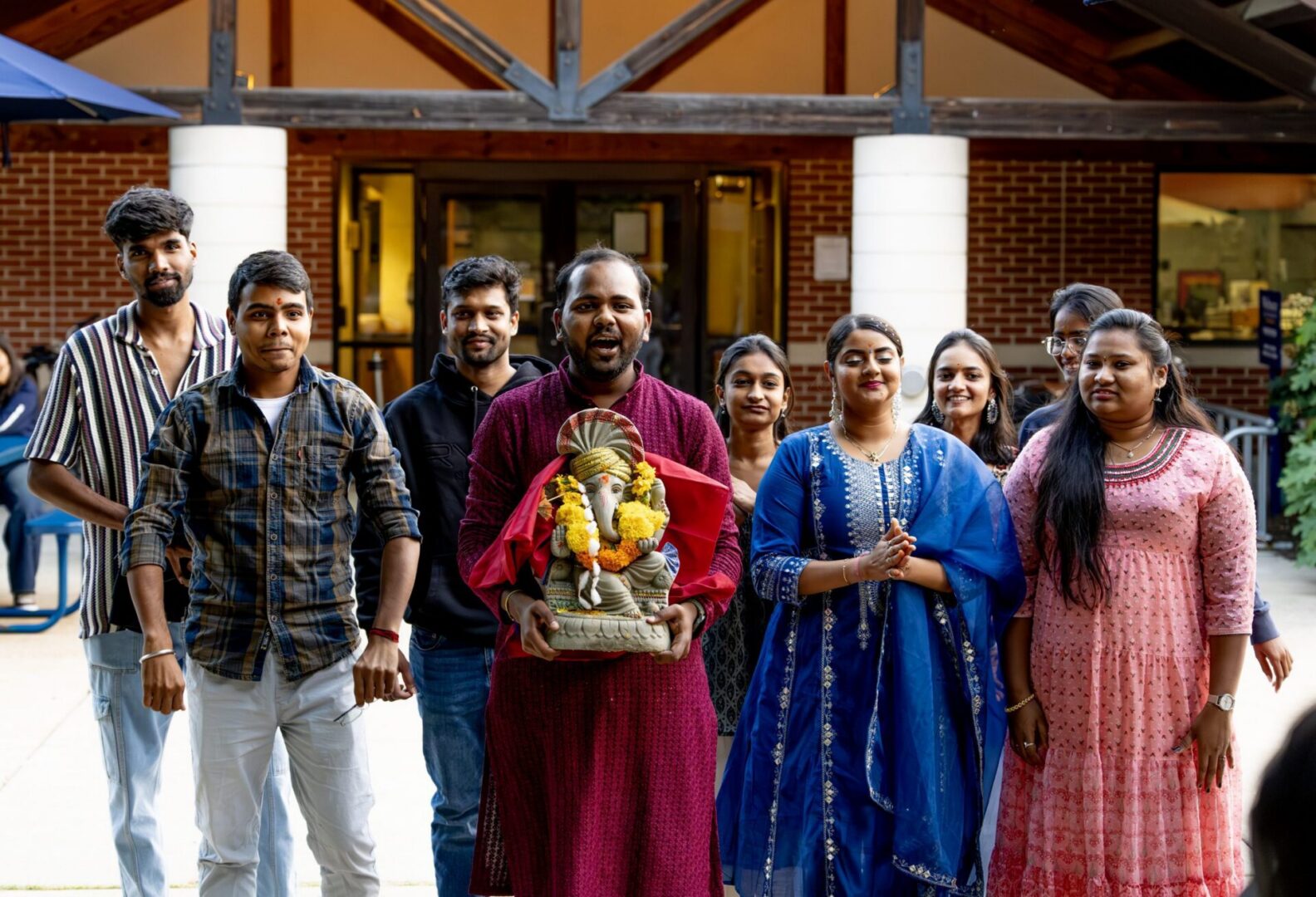 People in colorful attire holding Ganesha
