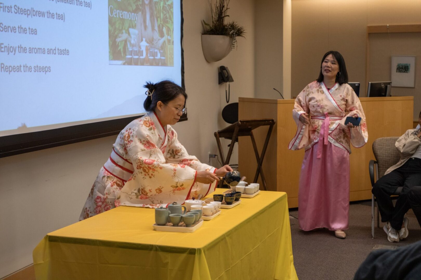 Tea ceremony presentation with two women in kimonos