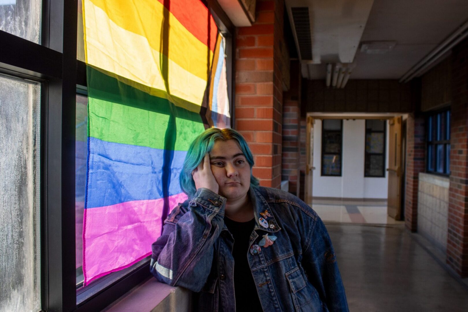 Contemplative person beside window with flag