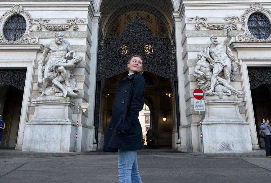 Tourist in black coat near decorative sculptures