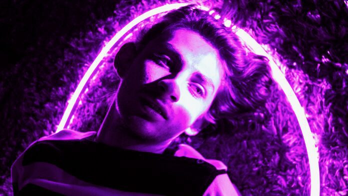 Man laying under pink neon glow