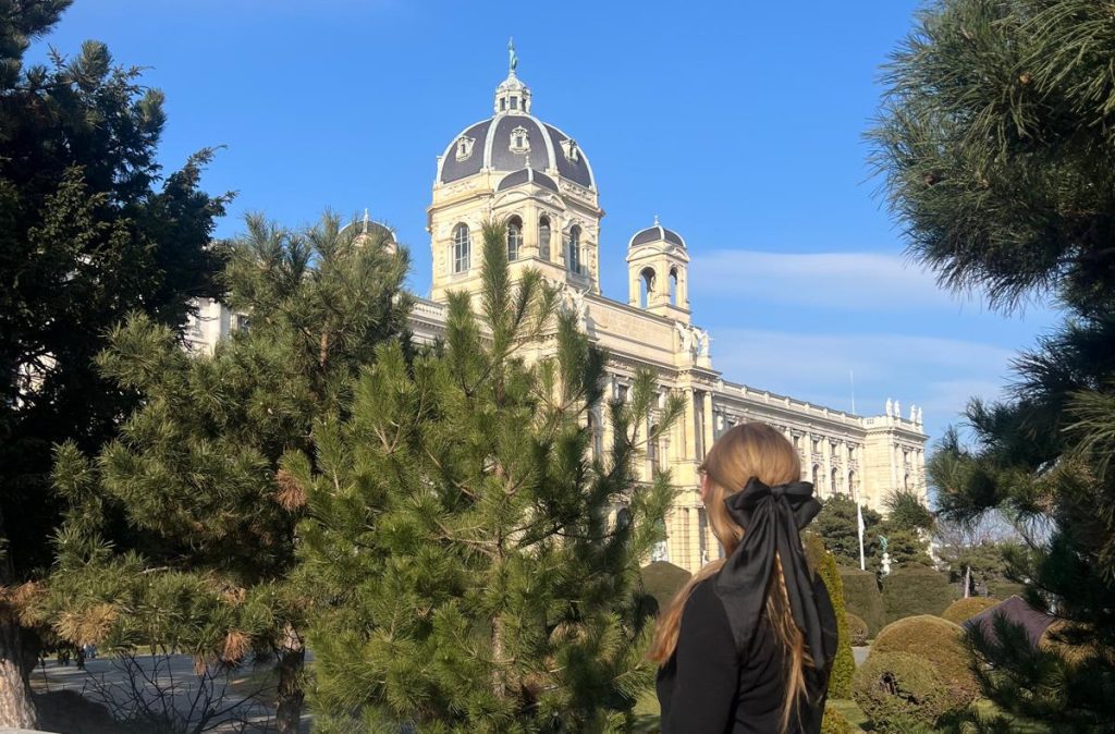 Person admiring historic building through trees