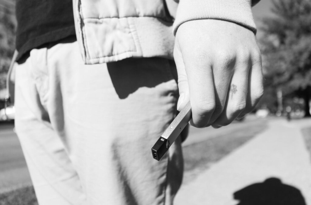 Person holding a vape on sidewalk