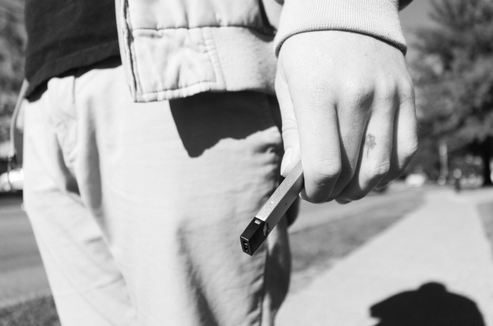 Person holding a vape on sidewalk
