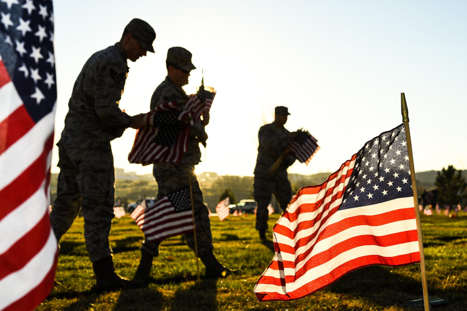 Soldiers placing American flags at sunrise.