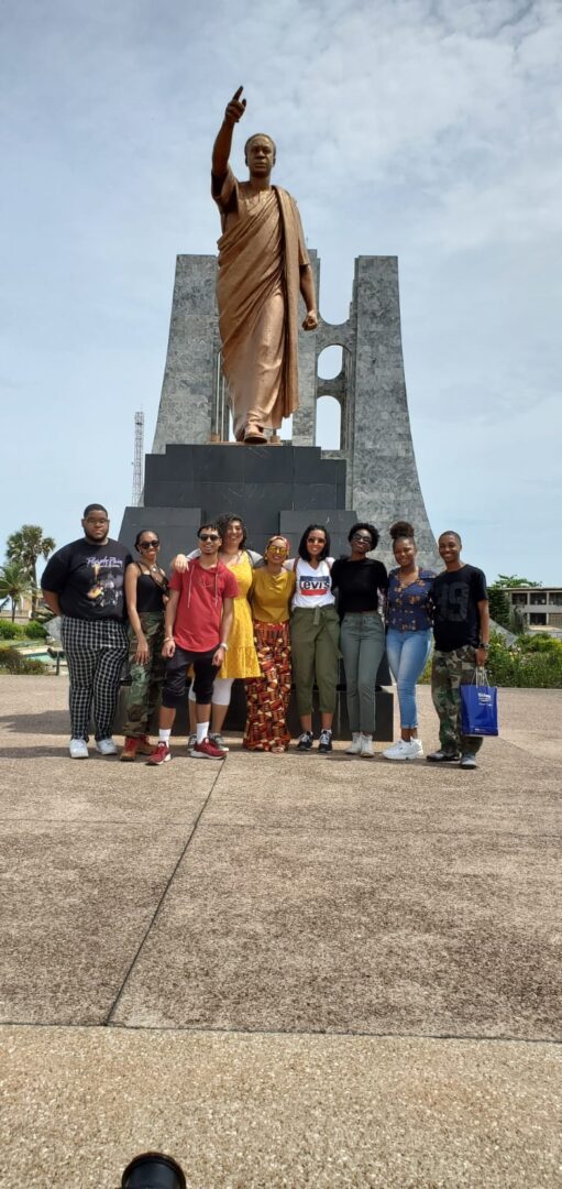 Group posing by a large statue