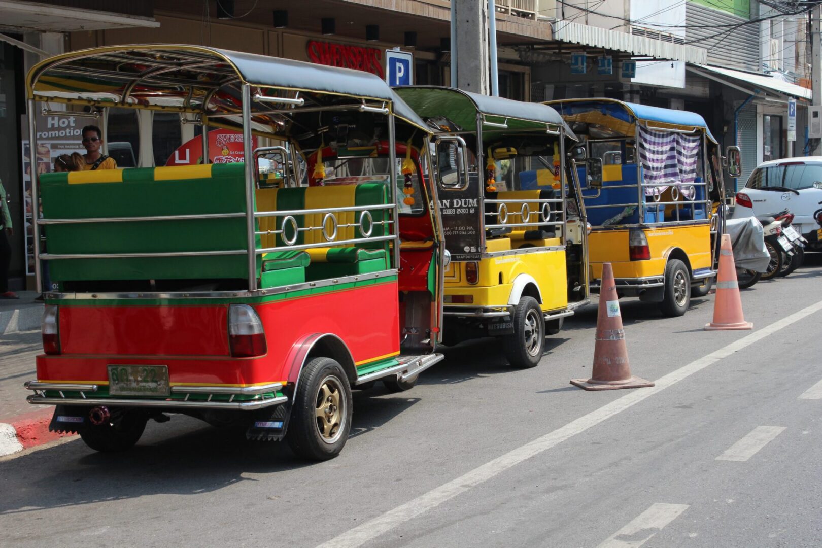 Tuk-tuks waiting by roadside cones