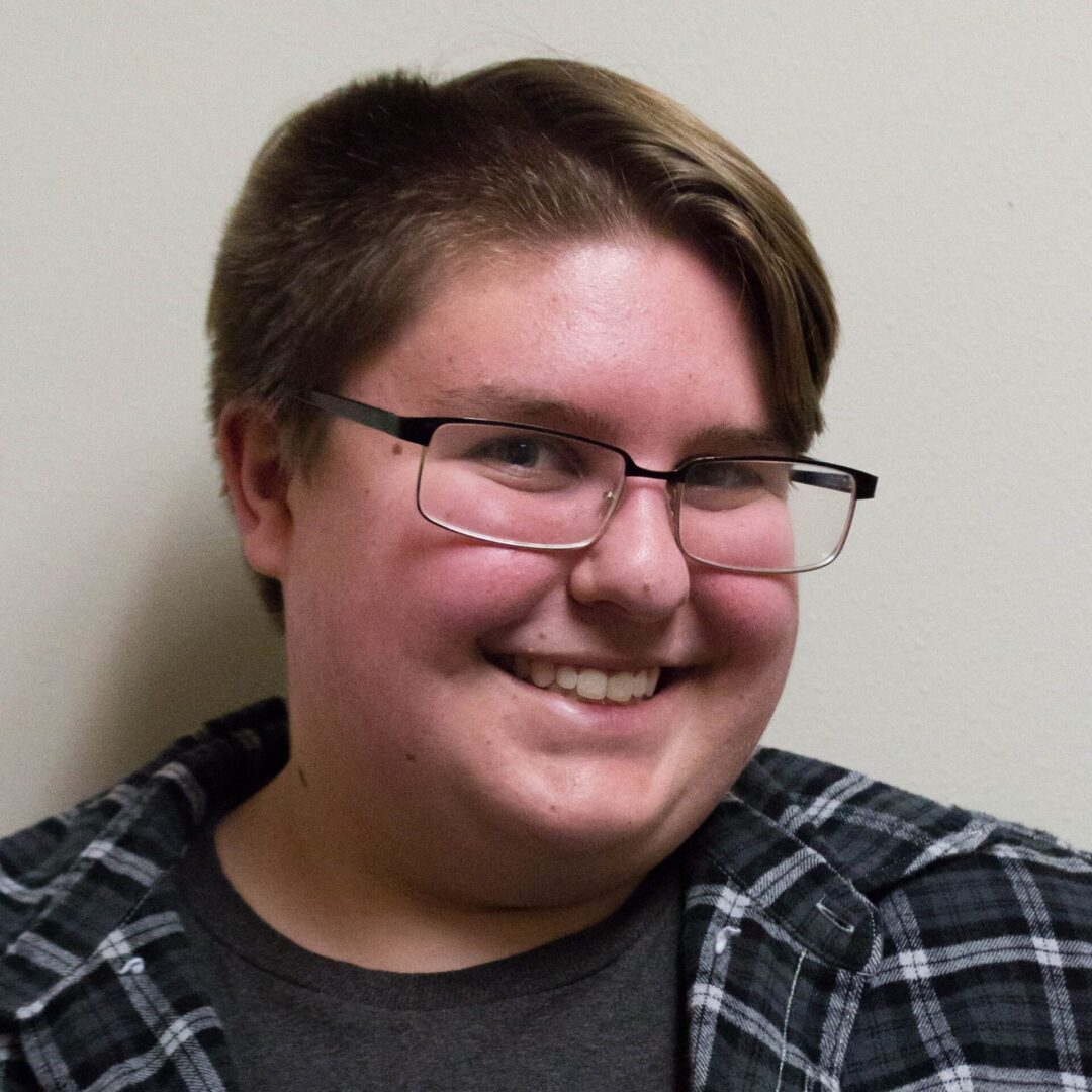 Smiling individual wearing a plaid shirt