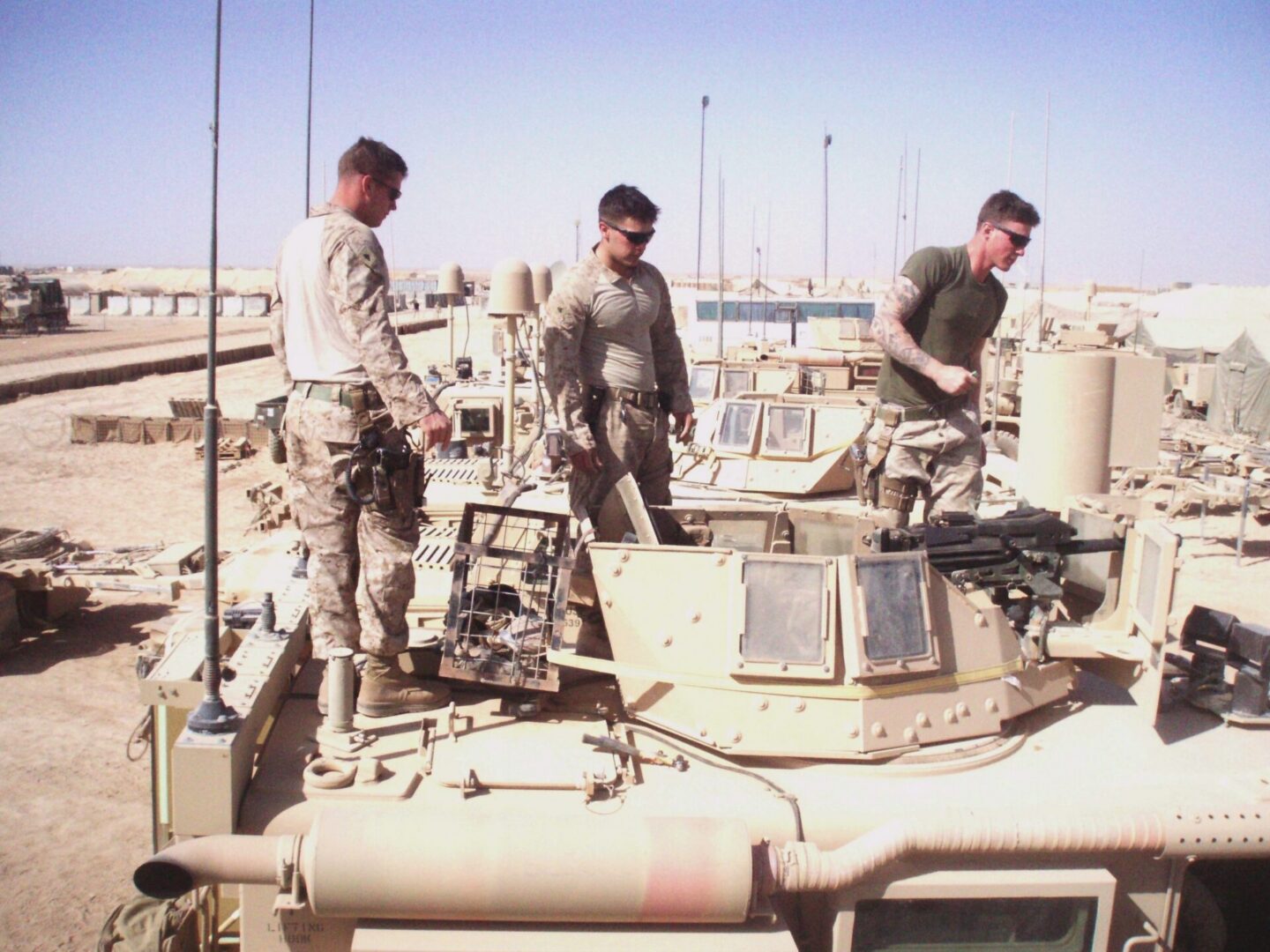 Military personnel on armored vehicle rooftop