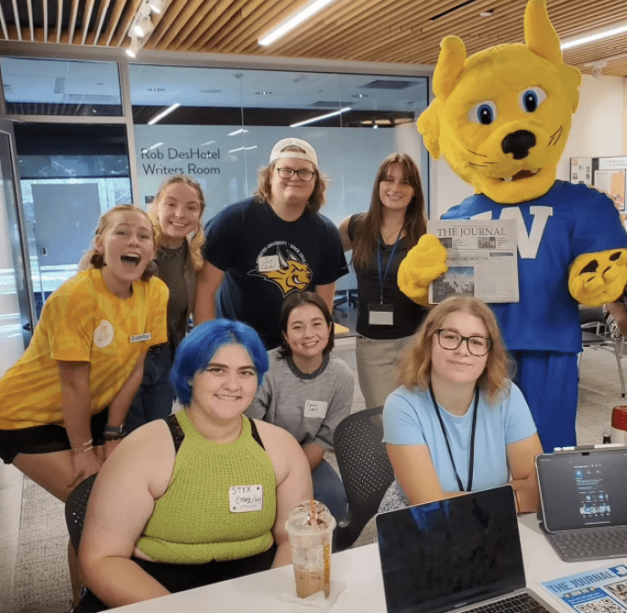 Students with mascot holding a newspaper