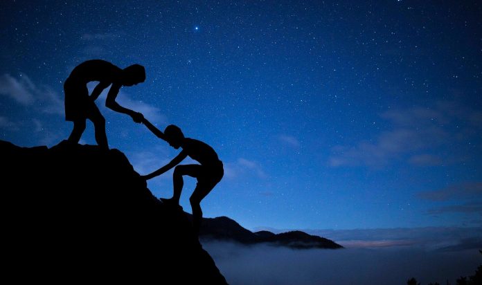 Silhouettes climbing under starry sky