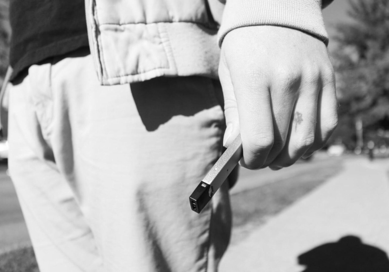 Person holding a vape on sidewalk
