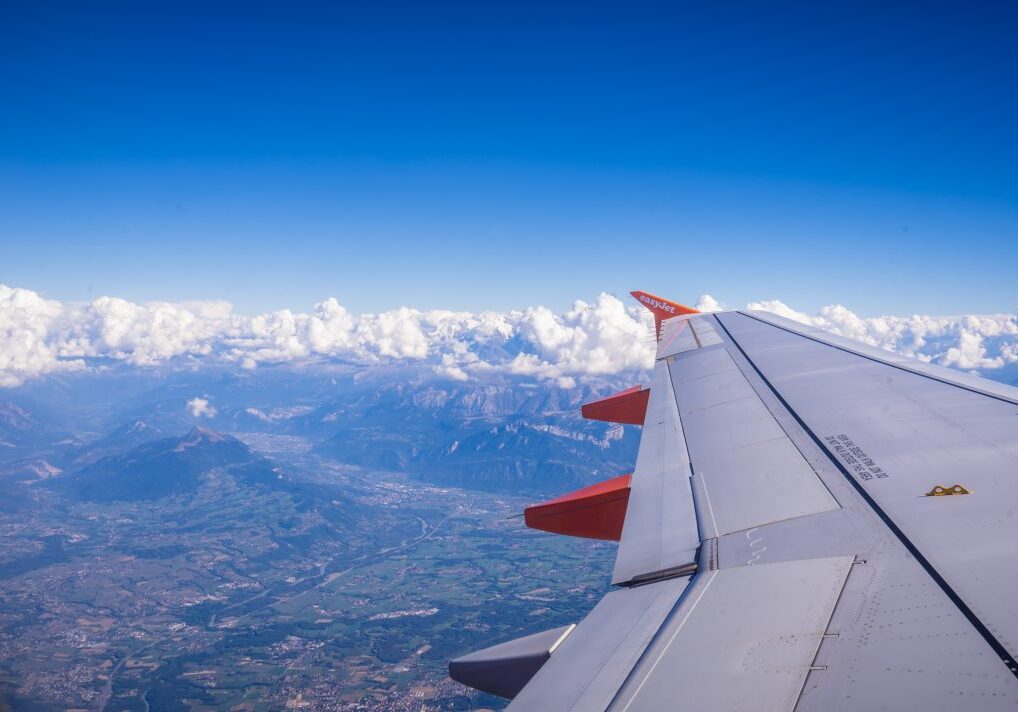 Airplane wing above clouds and mountains