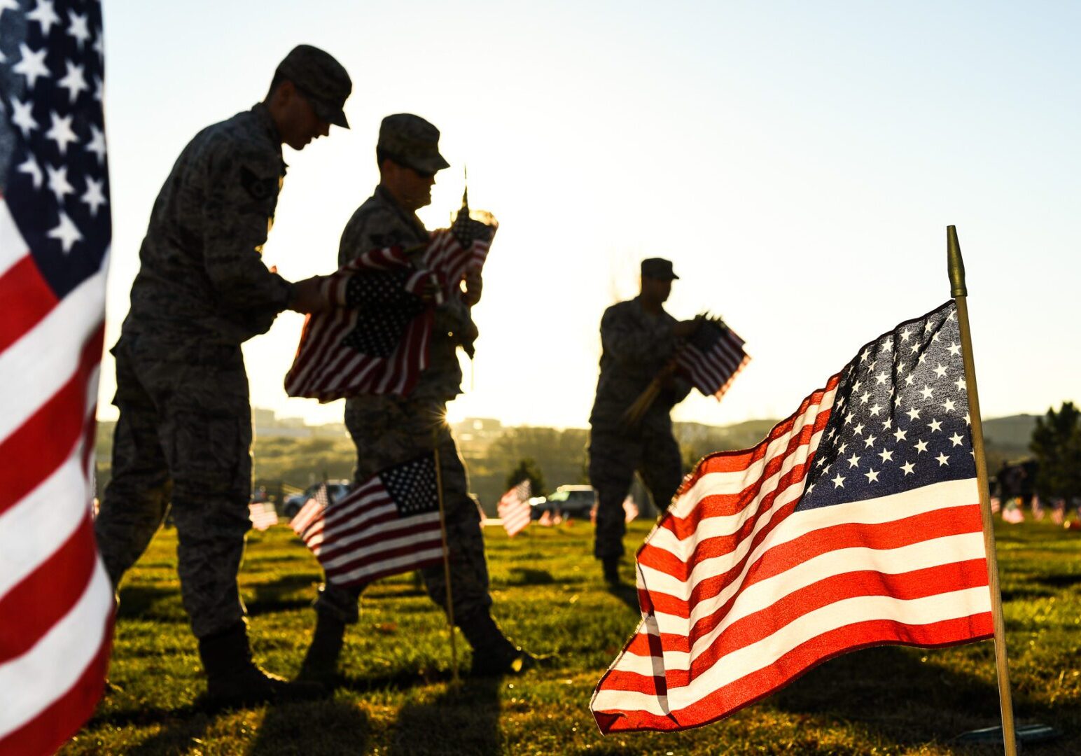 Soldiers placing American flags at sunrise.