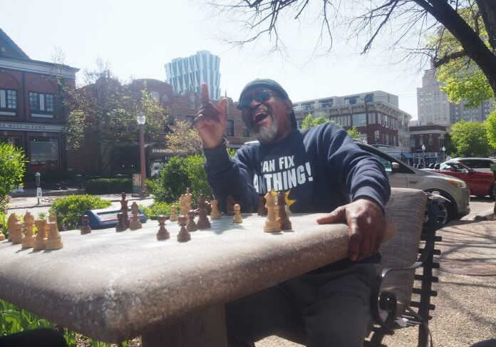 Man laughing during outdoor chess game