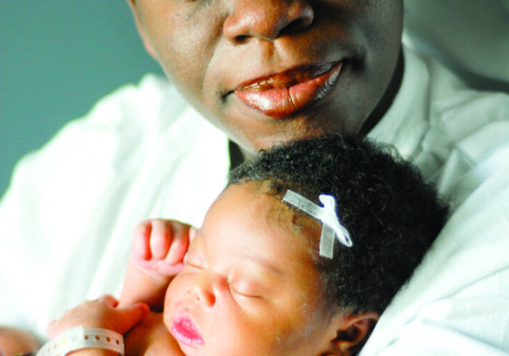 Parent cuddling infant with bow