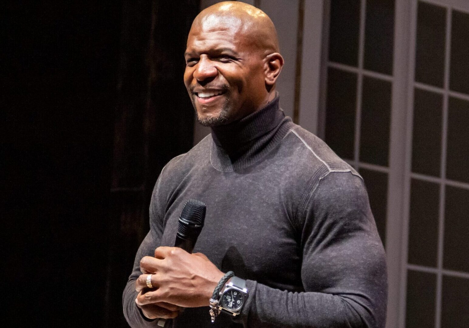 Man smiling while holding a microphone