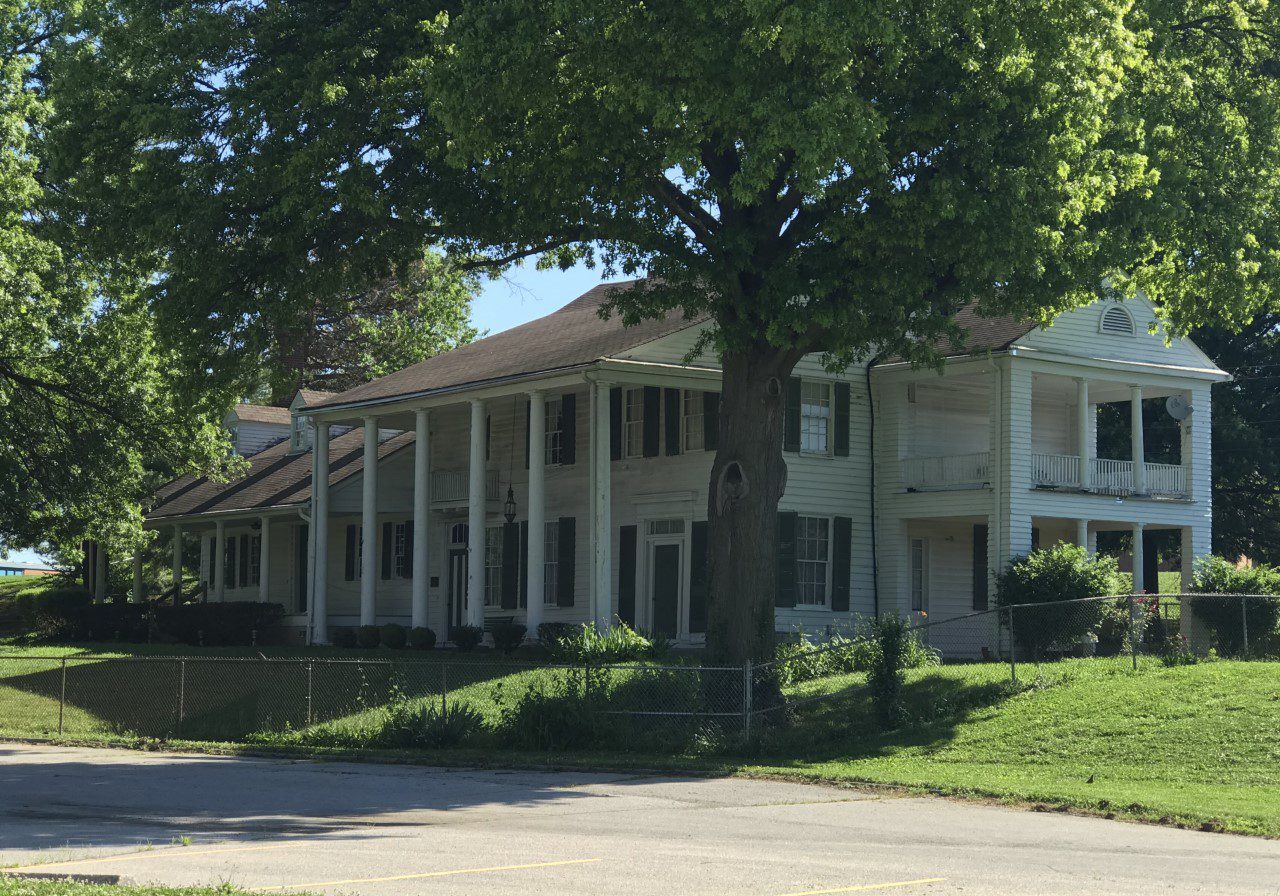 Two-story house with columns and greenery