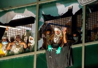 Protesters behind broken window with sign