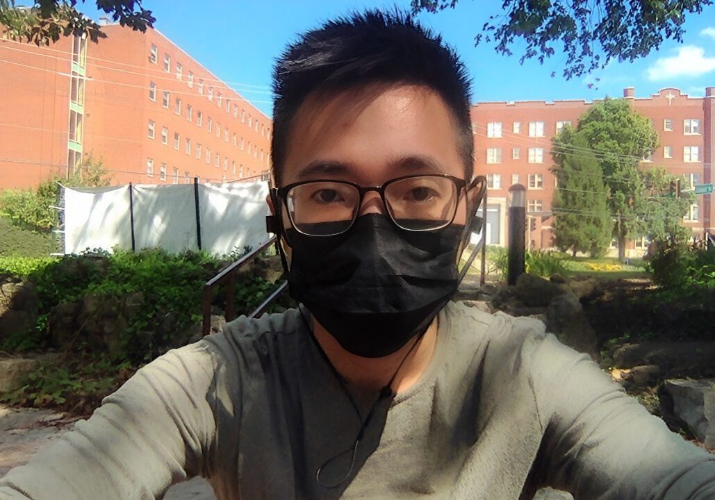 Masked person sitting outside in daylight