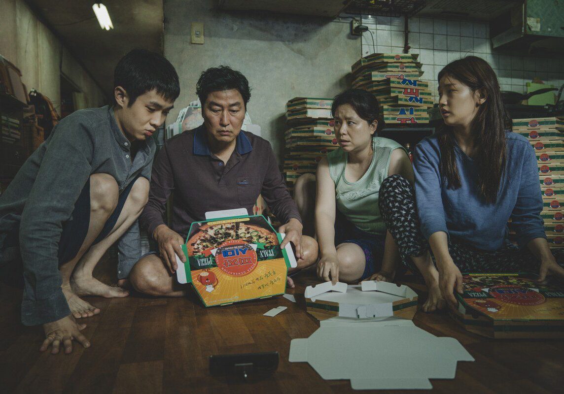 Four people focused on pizza boxes