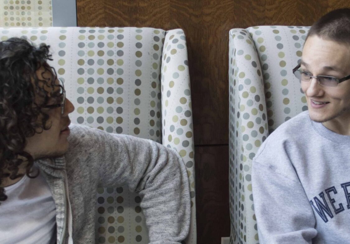 Two people chatting on patterned chairs.