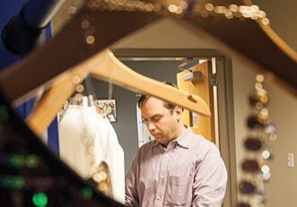 Man behind clothes hangers in fitting room