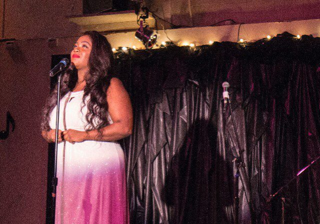 Woman in pink dress singing on stage