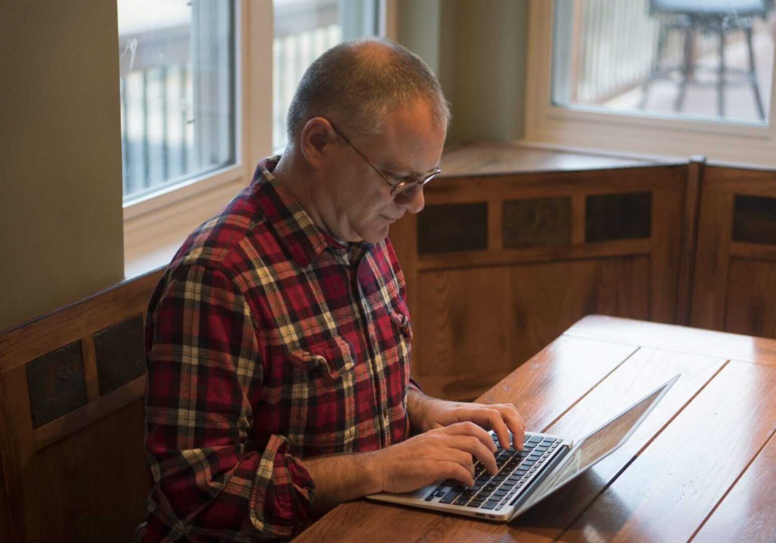 Individual in plaid shirt using laptop.