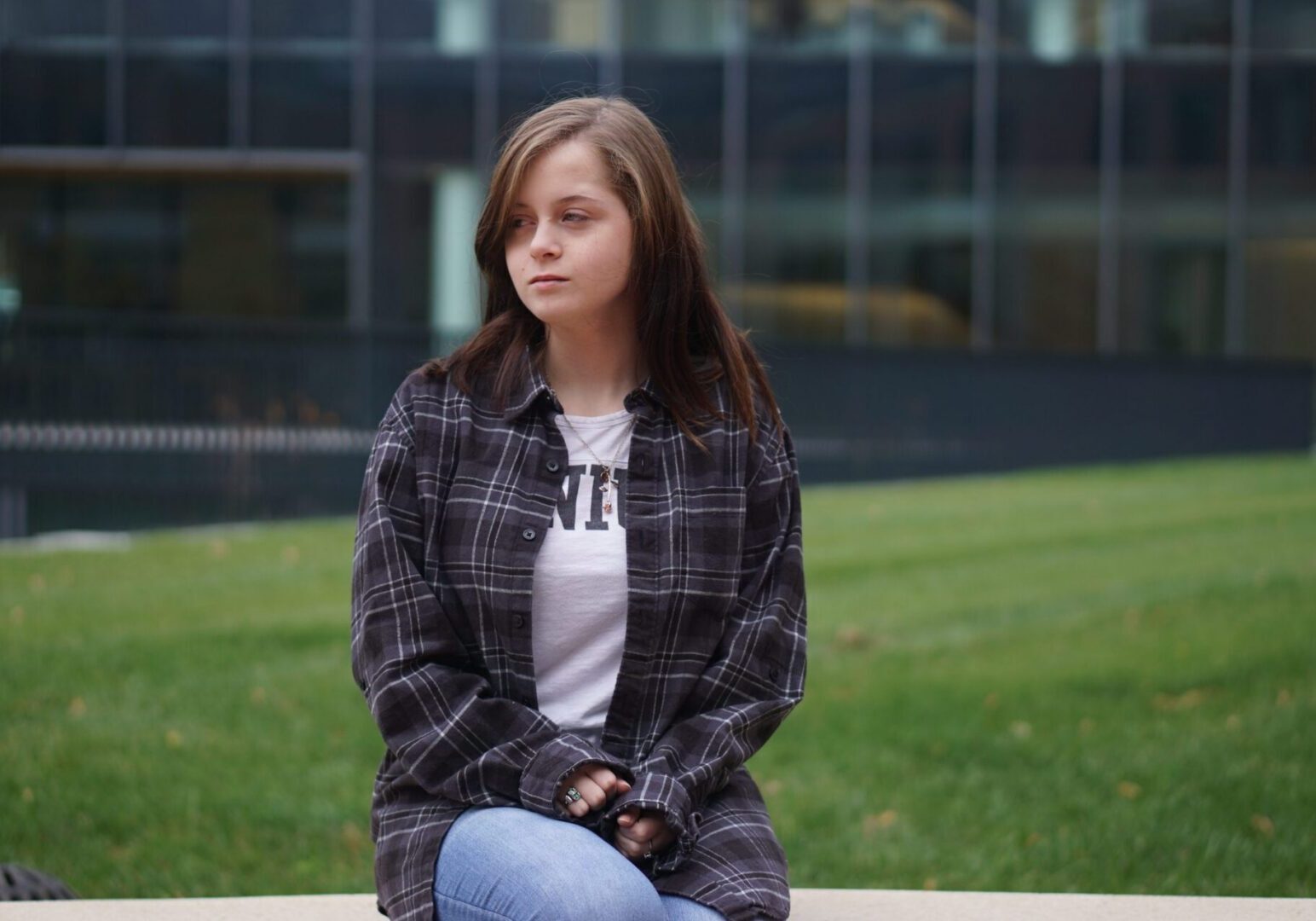 Woman in plaid shirt on campus.