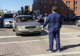 Person standing in city street before stopped car