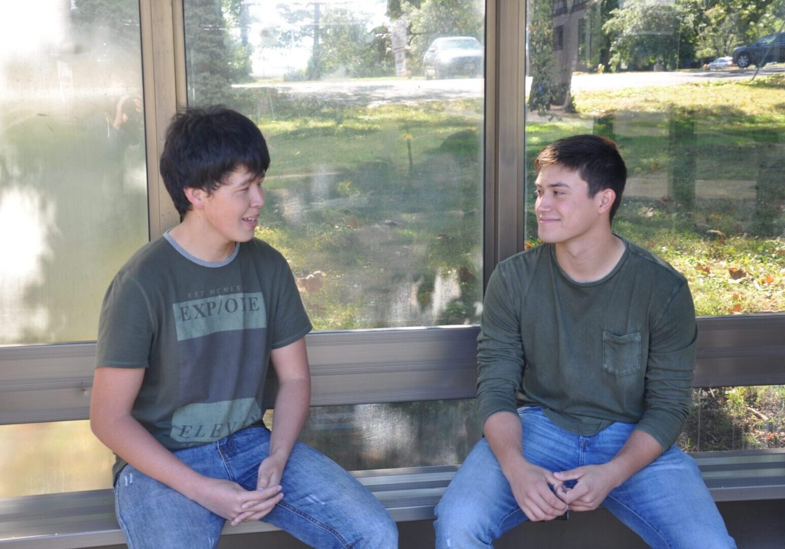 Two people talking by a window.