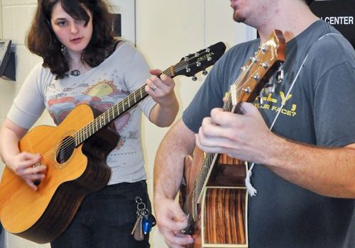 Musicians practicing with acoustic guitars together.