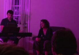 People performing music in purple-lit room