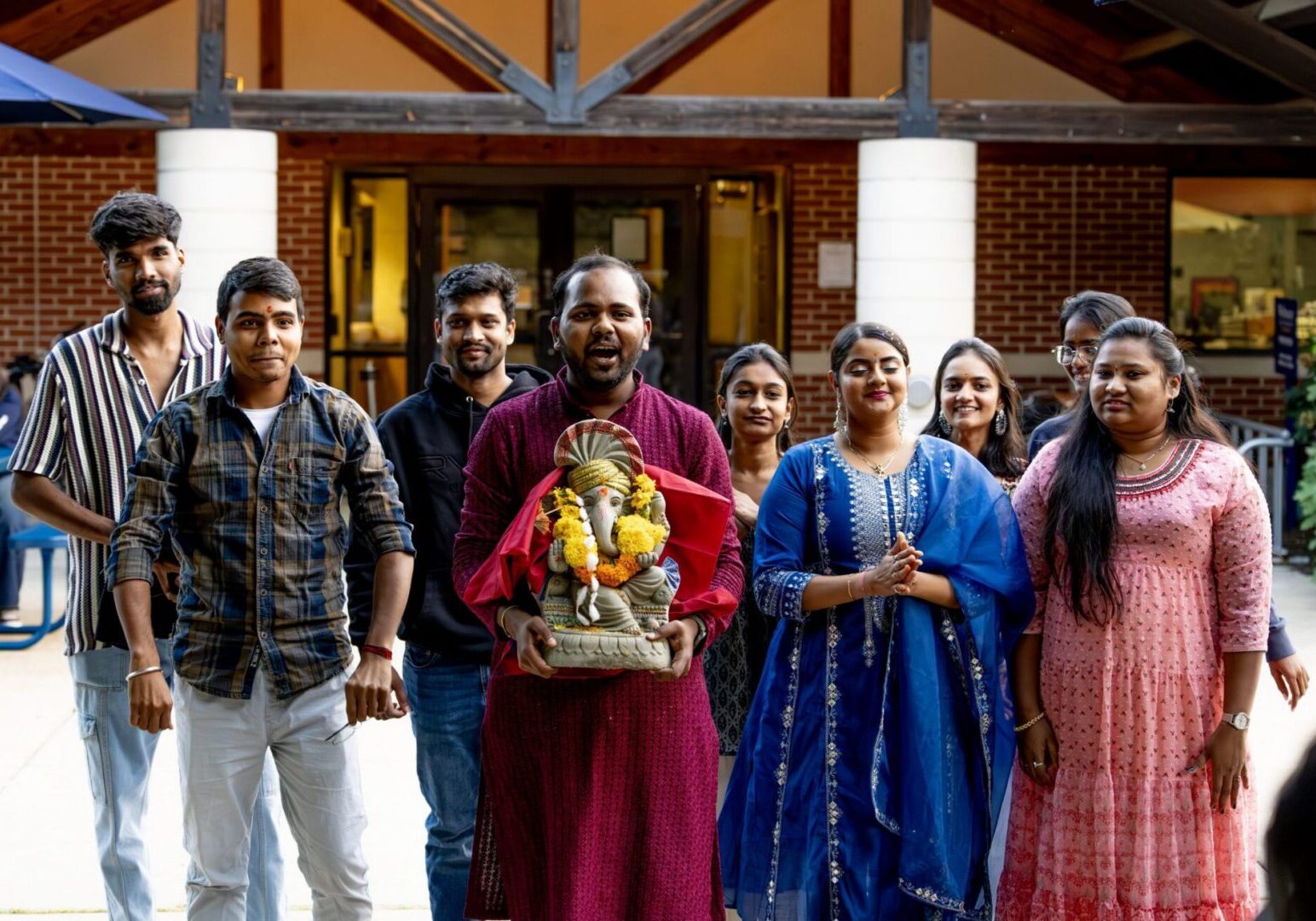 People in colorful attire holding Ganesha