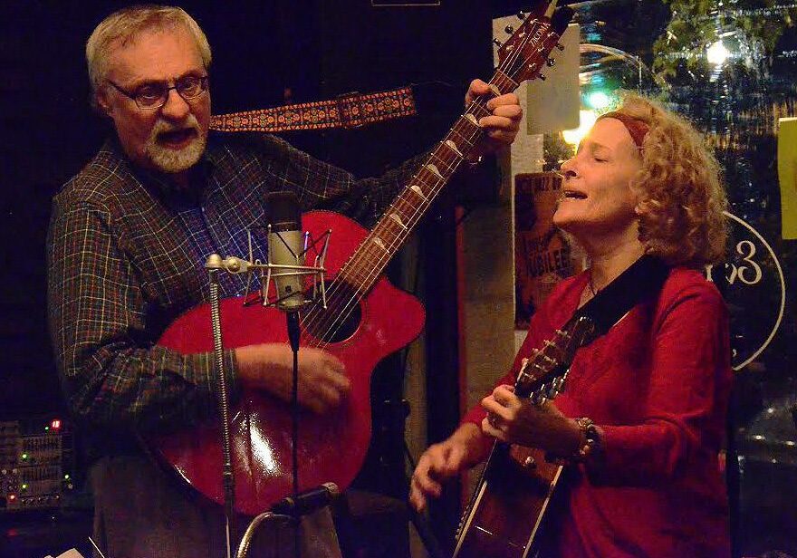 Duo performing with guitars on stage