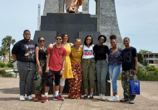 Group posing by a large statue