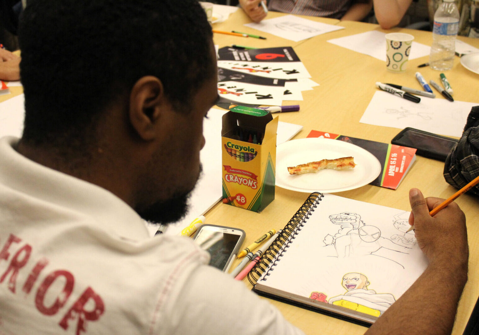 Artist focused on sketching with crayons nearby