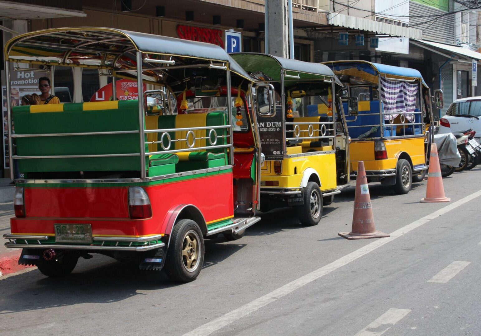 Tuk-tuks waiting by roadside cones