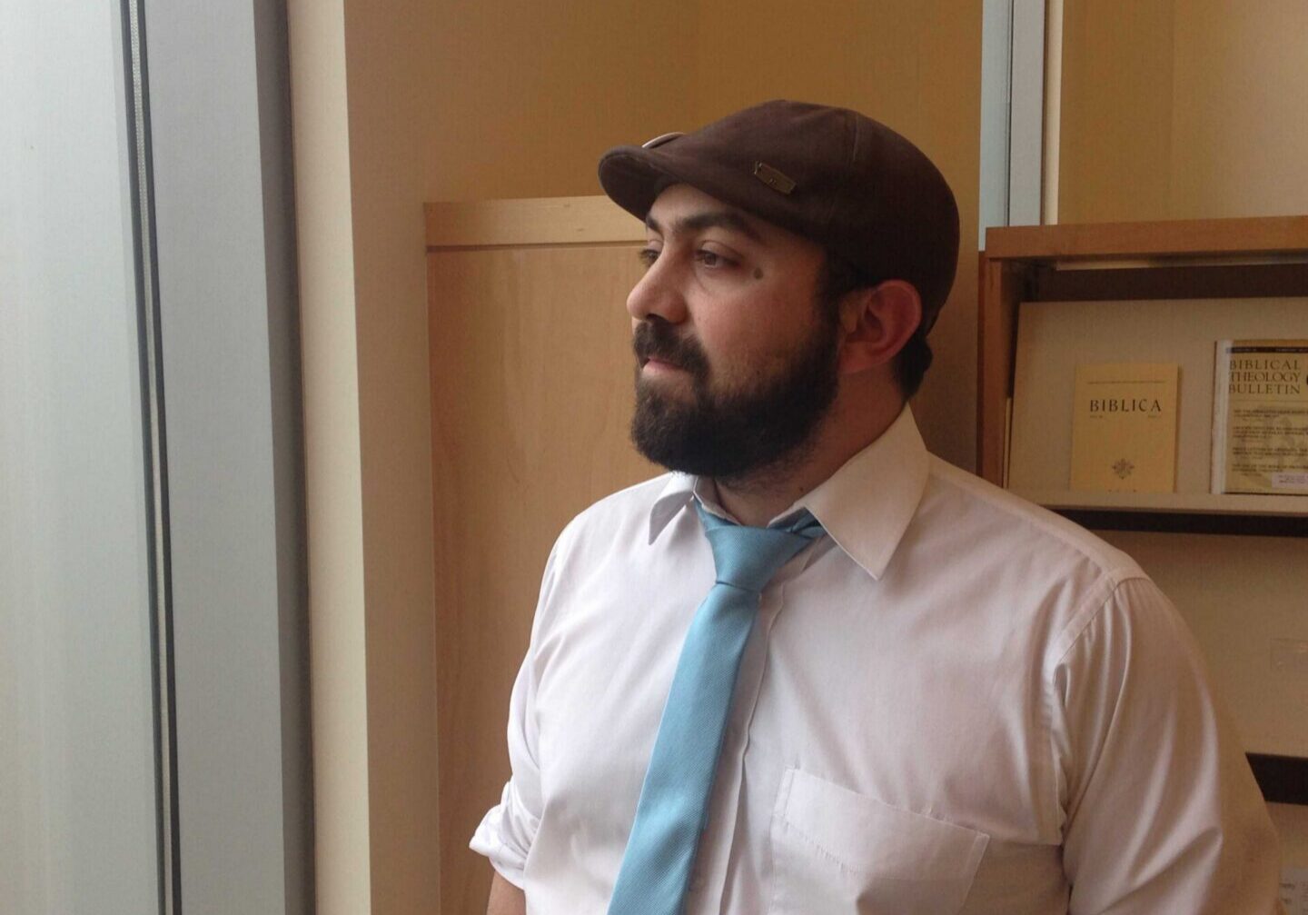 Bearded man in tie near bookshelves