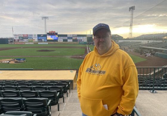 Man in yellow hoodie at baseball stadium