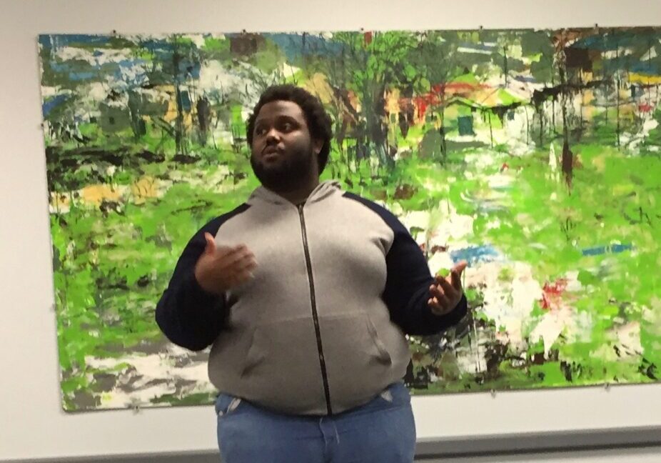 Speaker gestures near colorful artwork