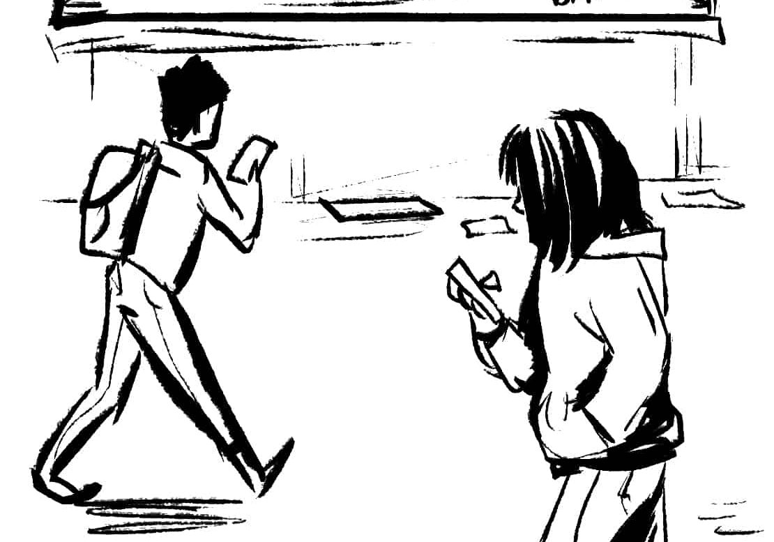 People checking phones near bulletin board.
