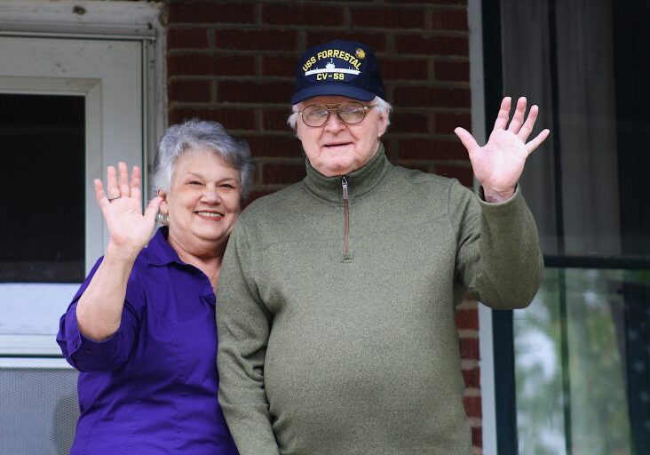 Elderly couple waving from porch